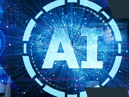 Centralnie umieszczony napis „AI” w otoczeniu cyfrowych efektów i niebieskich świateł, na tle licznych paneli technologicznych—np. sylwetki ludzkiej głowy, wykresów, danych binarnych oraz elementów związanych ze sztuczną inteligencją.